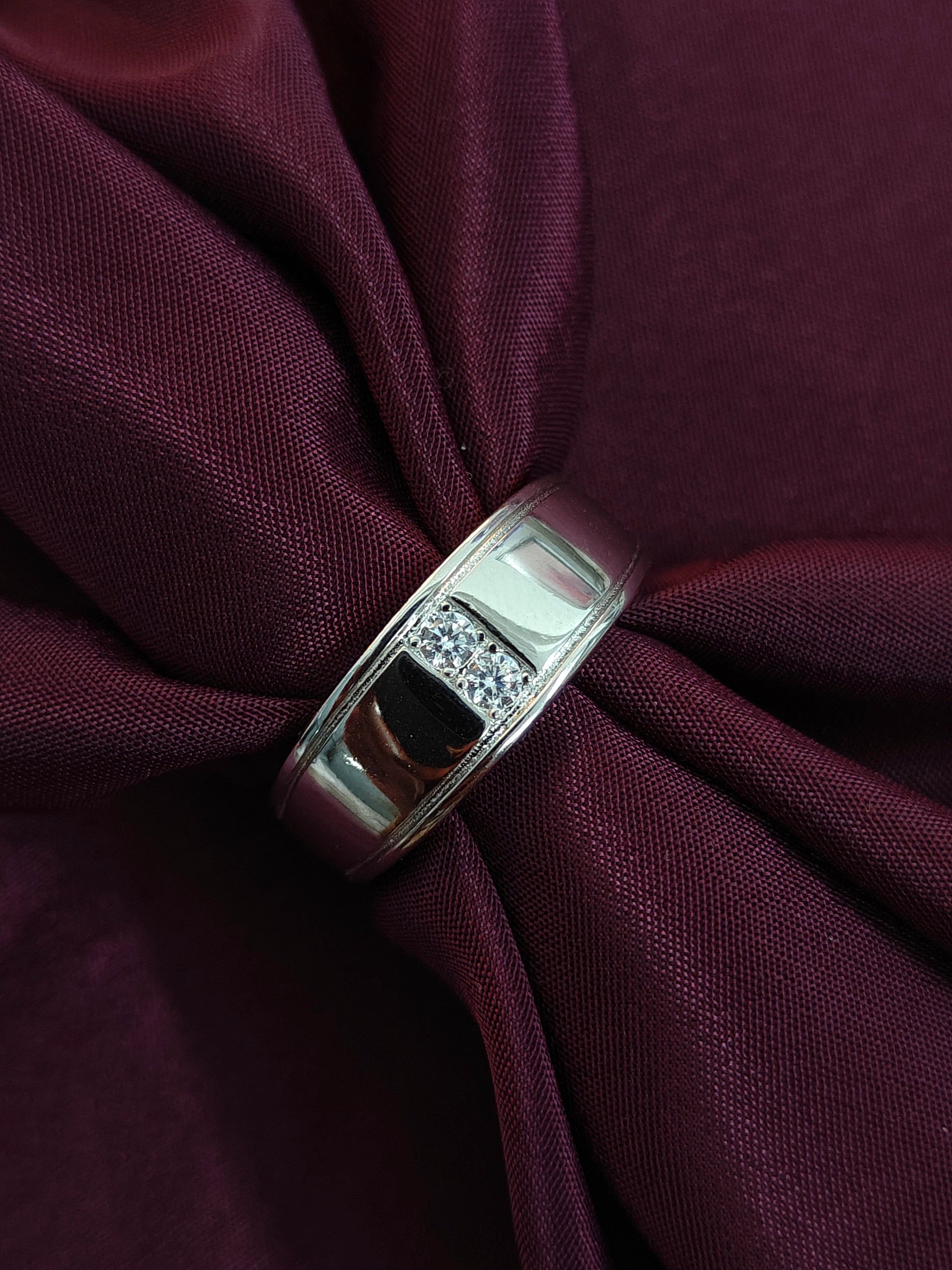 Silver ring with embedded stones on a burgundy fabric background
